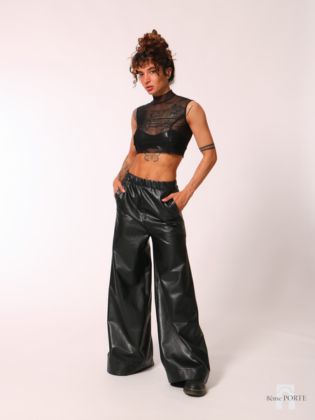 Front view of Ishtar & Brute loose-fit faux leather wide-leg joggers with hands in pockets, styled casually with chunky flat boots for a relaxed look.
