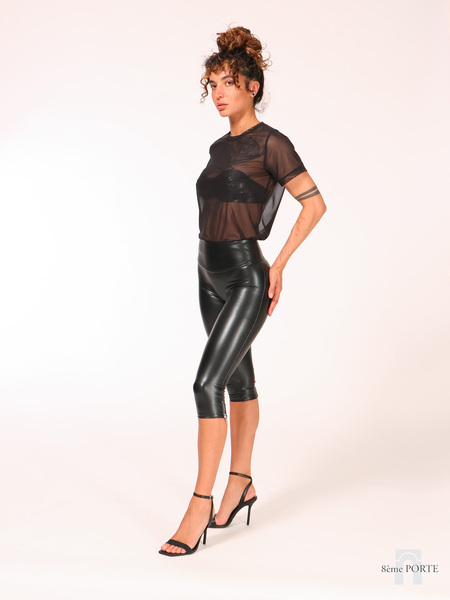 Left profile view of high-waist faux leather capri leggings highlighting the leg contour seams and metallic accent zipper along the outer calf hem.