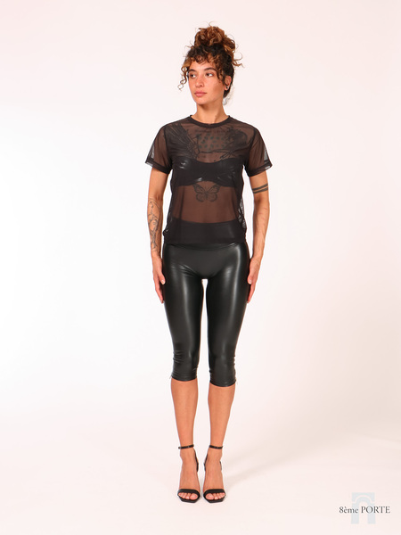 Full front view of model wearing the loose fit black mesh t-shirt layered over a bandeau bra with high-waisted Flora faux leather capri pants.