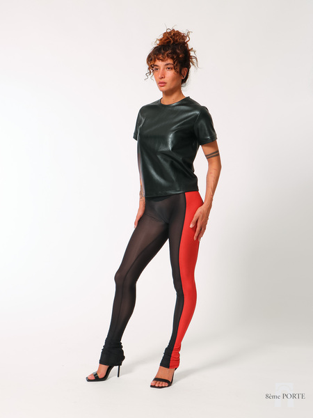 Front view of model wearing low-waisted black sheer leggings with a red side panel, paired with a loose-fit faux leather midi t-shirt.