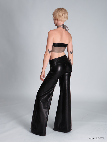 Full back view of pocketless faux leather pants paired with a sky grey translucent latex halter top and a black censor strip across the back.