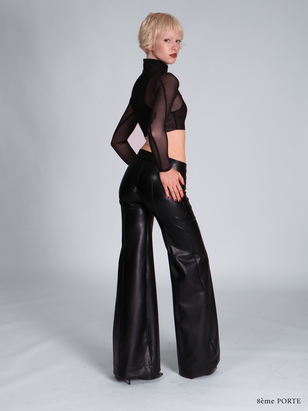 Rear view of custom made-to-measure faux leather jean pants showing a seamless pocket-free back, paired with a black double mesh halter crop top.